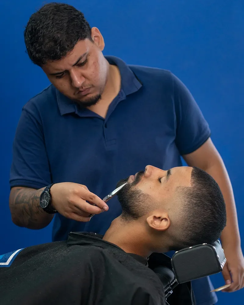 Barbeiro fazendo barba na navalha